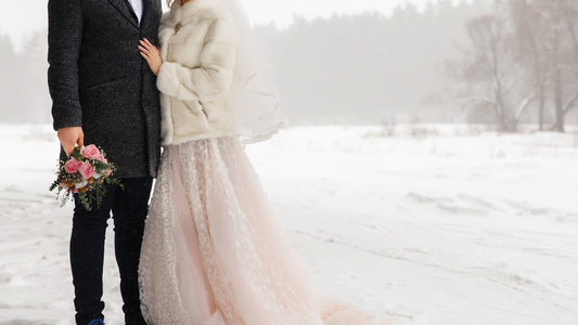A bride and groom standing in front of a snow covered field