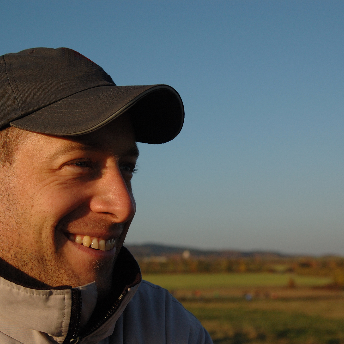 Man wearing a baseball cap with scenery behind him