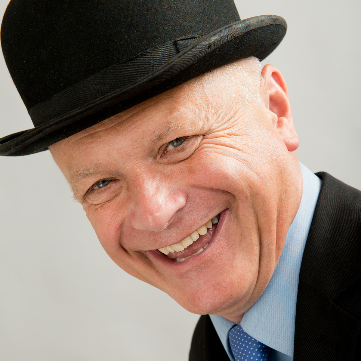 A smiling man wearing a bowler hat