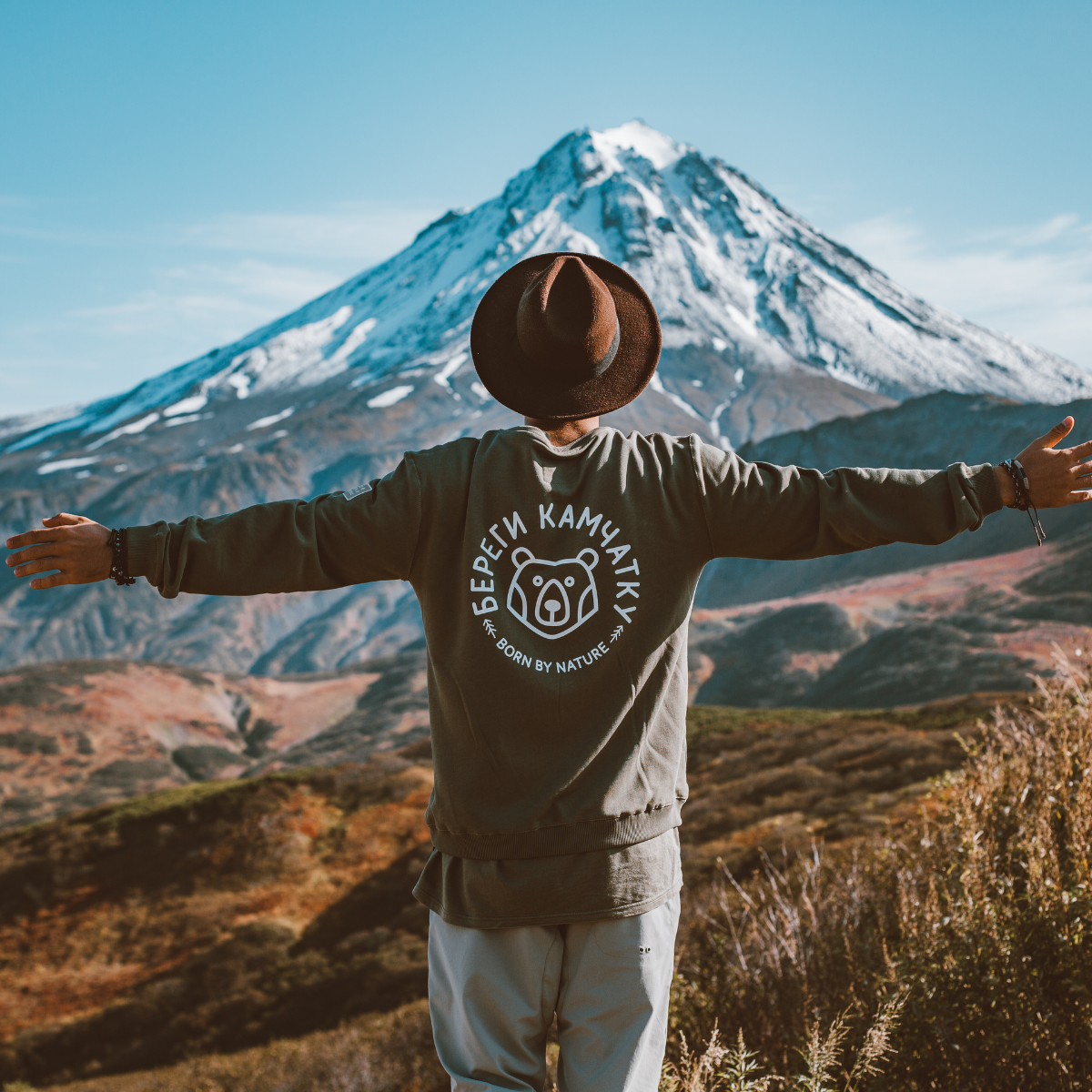 A man wearing a brown hat, in front of a mountain