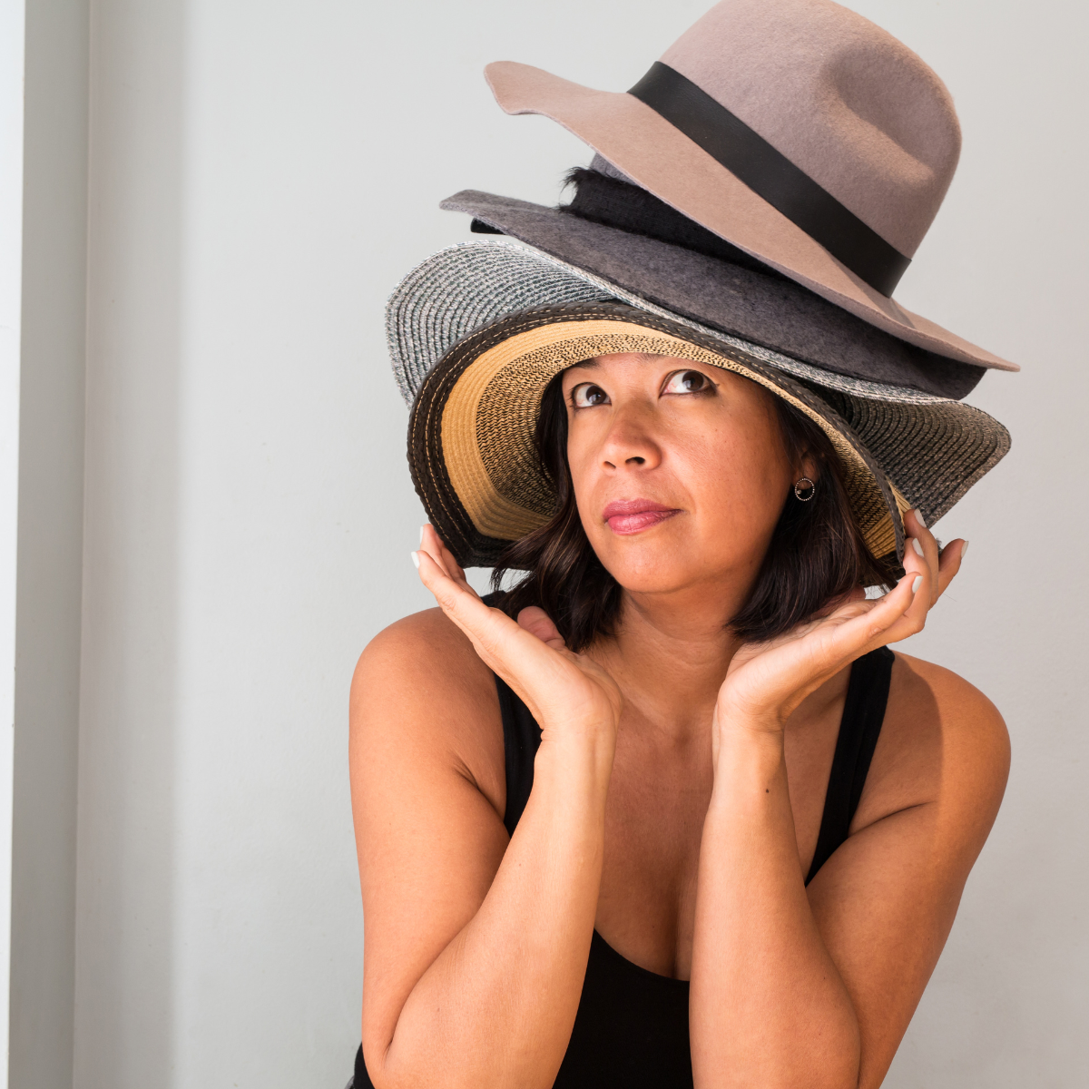 A lady with several types of hat piled on her head