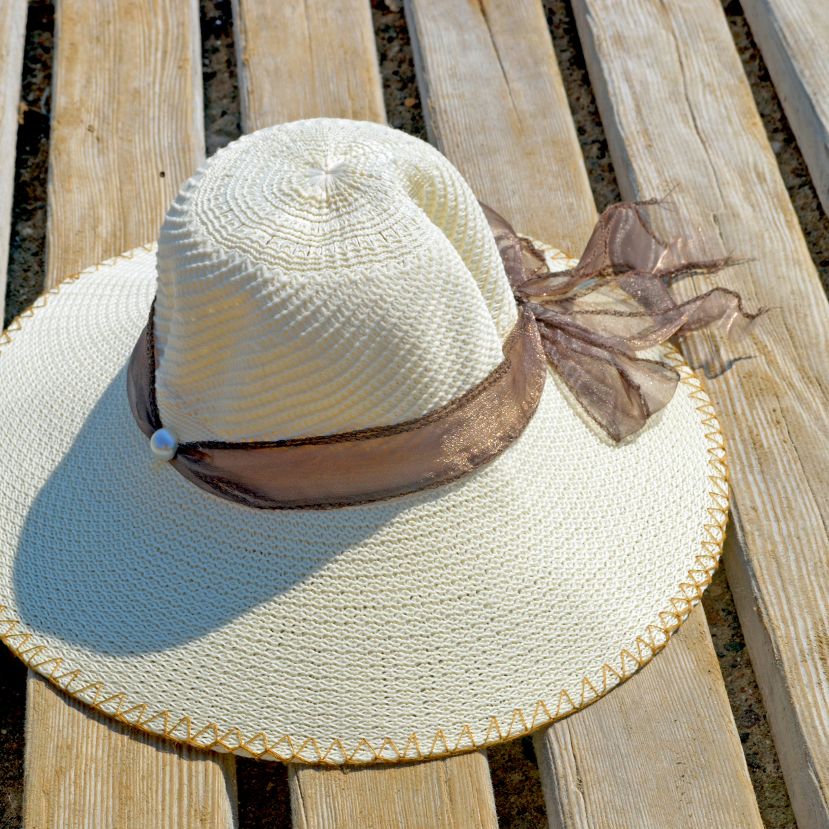A lady's sun hat sitting on a bench