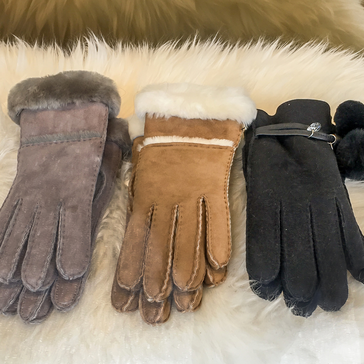 Three pairs of leather gloves for women laying on a sheep skin rug