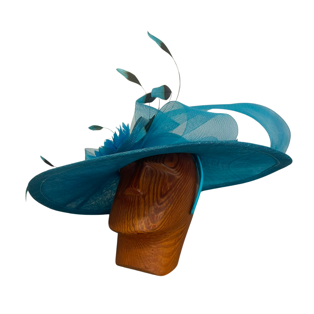 A bright turquoise blue fascinator hat displayed on a brown wooden mannequin head against a plain white background. The hat features a wide brim, sheer mesh ribbon, feather accents, and leaf-like decorative elements.