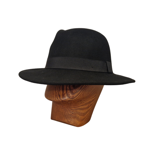 A black felt fedora hat with black ribbon band displayed on a wooden mannequin head against a plain white background.