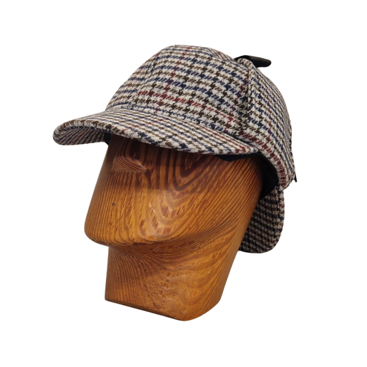 A classic deerstalker hat with a grey,  brown, black, and white houndstooth pattern, displayed on a wooden mannequin head against a plain white background.